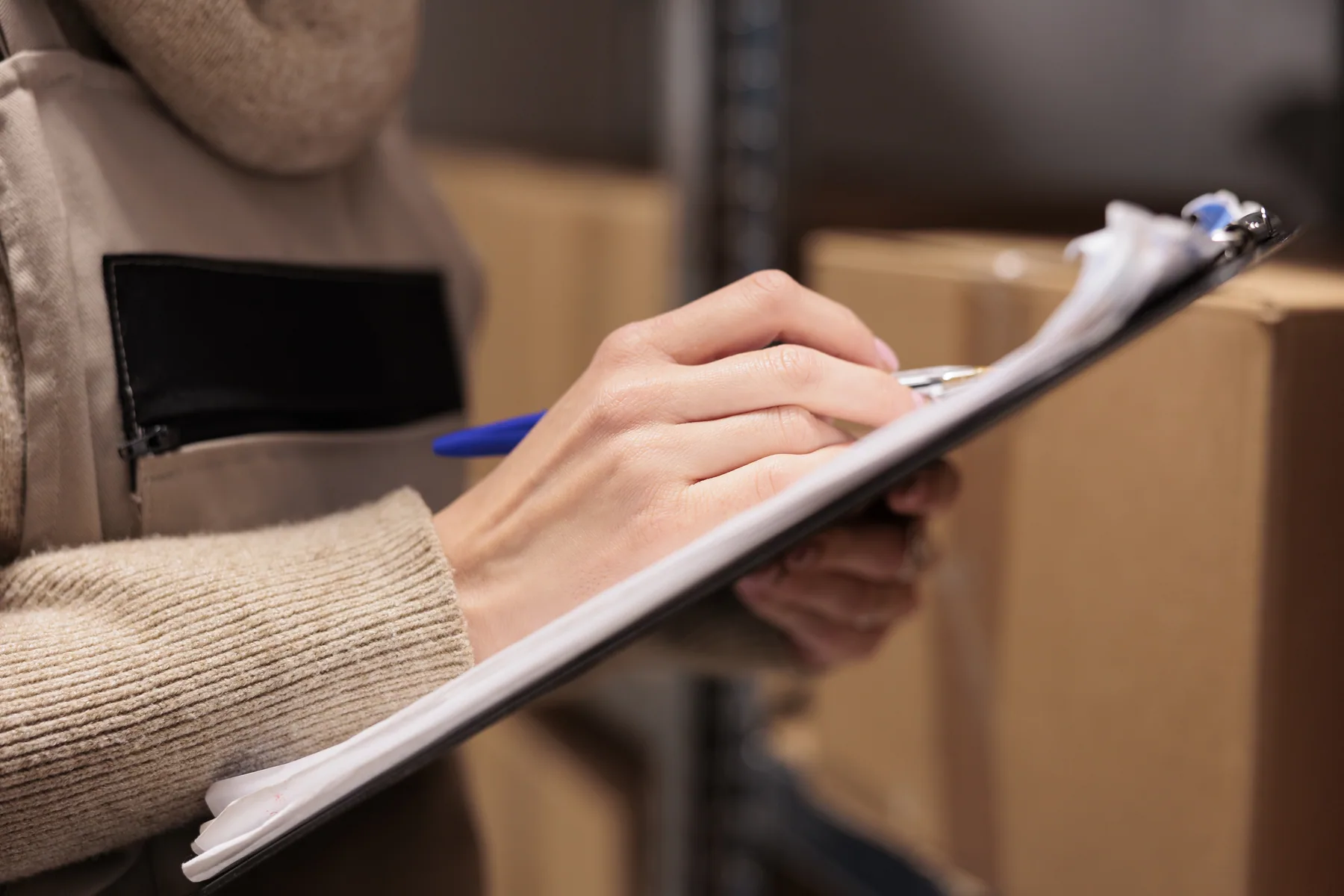 Filling in a clipboard beside stacked cardboard boxes