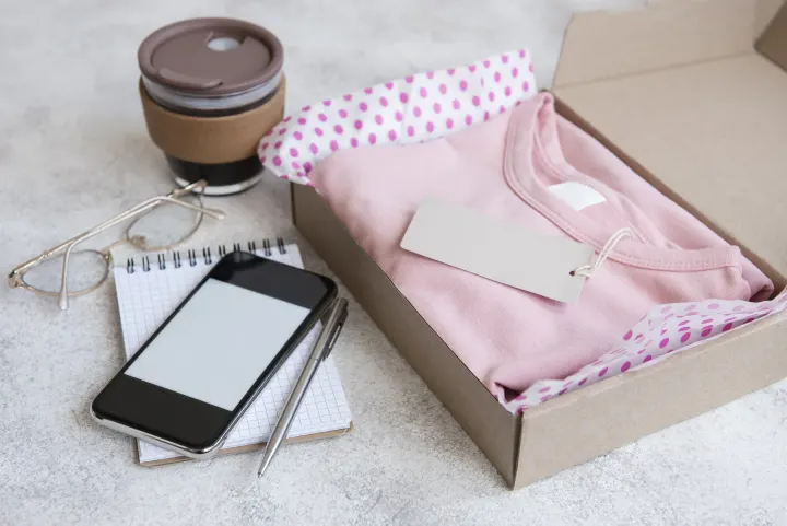 A folded pink garment packed in an open shipping box